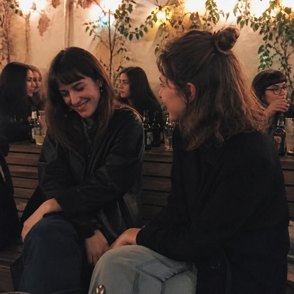 Una ragazza ride durante un aperitivo raccolto a luci soffuse in compagnia di altre donne